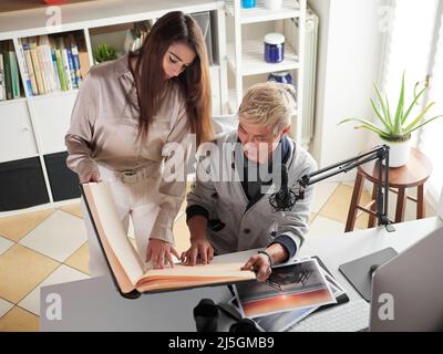 Fotografen, die am Arbeitsplatz mit zwei Computern im Studio mit einem Laptop arbeiten Stockfoto