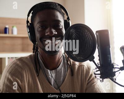 Afroamerican glücklich junge männliche Aufnahme Audio-Blog in Kopfhörer Mikrofon zu Hause senden ... Stockfoto