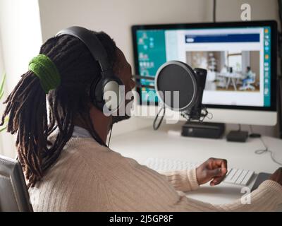 Afroamerican glücklich junge männliche Aufnahme Audio-Blog in Kopfhörer Mikrofon zu Hause senden ... Stockfoto