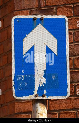 Verwitterte Richtungsschild mit rotem Backstein Hintergrund. Stockfoto