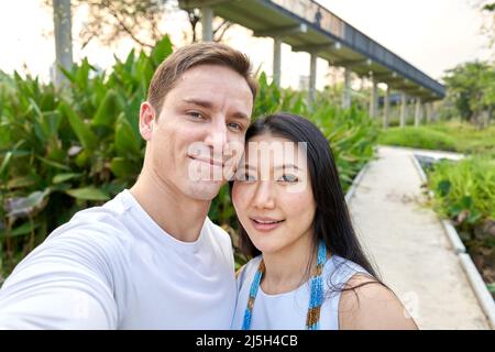 Newlyweb multirassisches Paar, das während des Sonnenuntergangs ein Selfie in einem Uran-Park gemacht hat Stockfoto