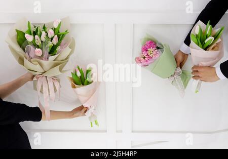 Blumensträuße im Frühling. Paar Mann und Frau Hände mit weißen und rosa Tulpen und Hyazinthen mono Bouquets halten. Stockfoto