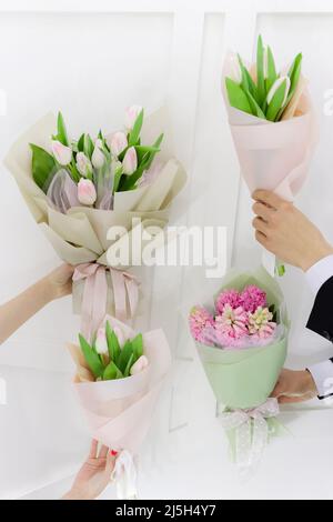 Blumensträuße im Frühling. Paar Mann und Frau Hände mit weißen und rosa Tulpen und Hyazinthen mono Bouquets halten. Stockfoto