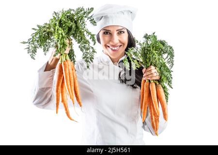 Fröhlicher junger Koch, der ein paar frische Karotten auf weißem Hintergrund hält. Stockfoto