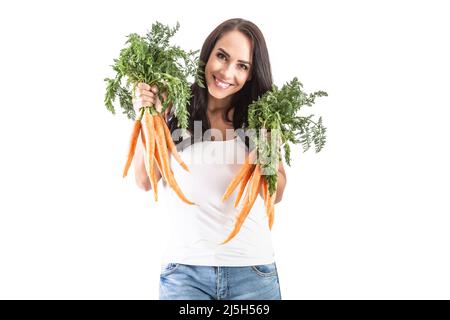 Fröhliche junge Frau, die ein paar frische Karotten auf weißem Hintergrund hält. Stockfoto
