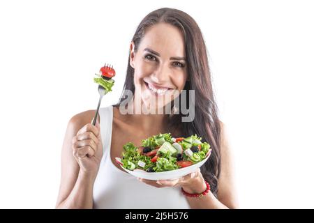 Lächelnde Brünette hält eine Gabel und isst gesunden vegetarischen Salat. Isoliert auf Weiß. Stockfoto