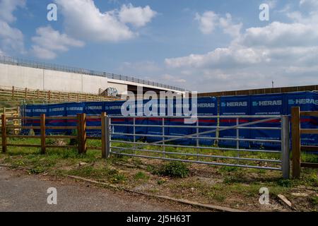 Dorney Reach, Buckinghamshire, Großbritannien. 23.. April 2022. Heras akustische Barrieren haben wenig getan, um Lärm aus den Werken zu verhindern. Das hübsche Dorf Dorney Reach ist jetzt nicht mehr zu erkennen mit der neu gebauten Brücke über die M4, die das Dorf mit riesigen Stützmauern und ungeeigneten Metallgeländern dominiert. Die M4 ist an diesem Wochenende wieder von der Abfahrt 6 (Slough/Windsor) zur Abfahrt 8/9 (Maidenhead) für M4 Smart Motorway Road Works geschlossen. Quelle: Maureen McLean/Alamy Live News Stockfoto