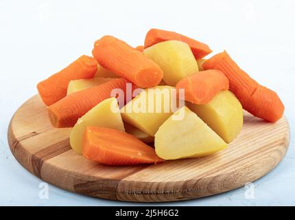 Gekochte Karotten und Kartoffeln für den Salat auf einem hölzernen Schneidebrett. Nahaufnahme. Stockfoto