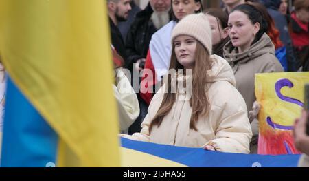 Mädchen auf dem Hintergrund einer gelb-blauen Flagge bei einer Kundgebung zur Unterstützung der Ukraine Stockfoto
