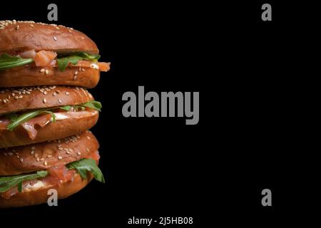 Nahaufnahme eines Sandwich-Bagels mit Lachs und Rucola auf einem dunklen Küchentisch Stockfoto
