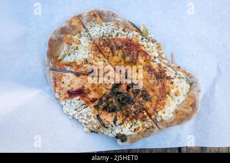 Draufsicht dünnes Brot oder Pizza mit Käse und saurer Rahm auf dem Papier. Stockfoto