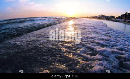 Sehr niedriger Winkel von Meereswellen, die auf einen Sandstrand stürzten. Stockfoto