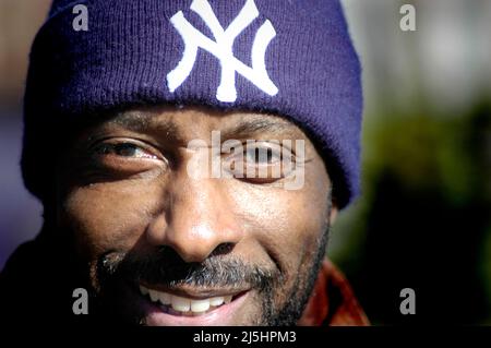 Gesicht in einer Menge von einem schwarzen afroamerikanischen Mann in den USA mit einer New York Yankee Strickmütze und einem Lächeln und Kopie und Text Hintergrund Stockfoto