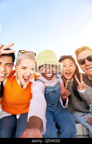 Vertikales, lächelndes Selfie einer glücklichen Gruppe multikultureller Freunde, die die Kamera betrachten. Porträt von fröhlichen multi-ethnischen jungen Menschen von verschiedenen Stockfoto