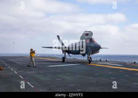 220411-N-IV962-2017 PAZIFISCHER OZEAN (11. April 2022) – Yuriy Dyshkant, der Partner des Chief Aviation Boatswain (Handling), leitet einen F-35B Lightning II, der dem Marine Fighter Attack Squadron (VMFA) 12aboard amphibischen Angriffsschiff USS Makin Island (LHD 8) zugewiesen wurde, 11. April. Piloten führen Qualifikationen zur Landung an Deck durch, um die Start- und Landungen an Bord zu üben. Makin Island ist ein amphibisches Angriffsschiff der Wasp-Klasse, das Routineoperationen in der US-Flotte von 3. durchführt. (USA Navy Foto von Mass Communication Specialist 3. Class Nadia Lund) Stockfoto