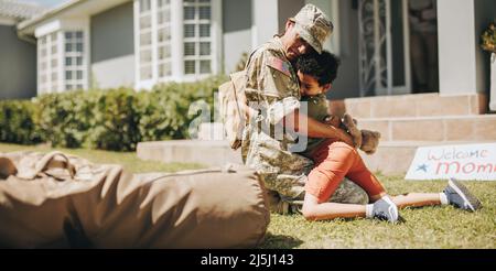 Mama vom Militär willkommen geheißen. Entzückender kleiner Junge umarmt seine Mutter auf ihrer Heimkehr. Militärische Mutter, die ein emotionales Wiedersehen mit ihrem Sohn a Stockfoto