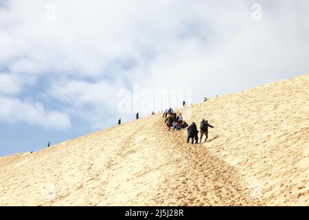 Bild von Menschen, die an einem sonnigen Nachmittag die Pyla Sand Düne erklimmen. Die Düne von Pilat (Dune du Pilat auf Französisch, oder Pyla) ist der höchste Sanddun Stockfoto