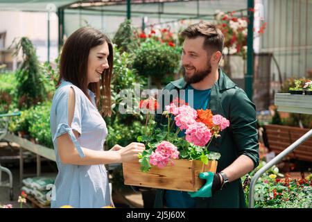 Mitarbeiter hilft weiblichen Kunden bei der Arbeit im Gartencenter Stockfoto
