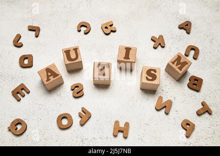 Wort AUTISMUS aus Würfeln und verschiedenen Buchstaben auf hellem Hintergrund Stockfoto