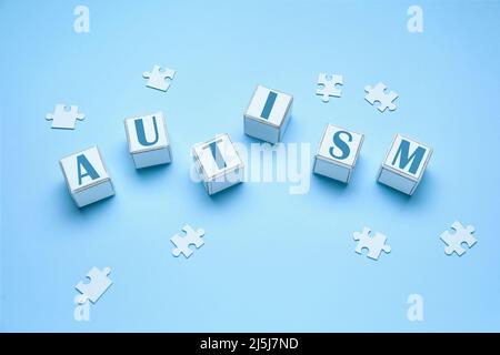 Wort AUTISMUS aus Würfel und Puzzleteilen auf hellblauem Hintergrund Stockfoto