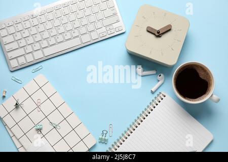 Rahmen aus Wecker, Tasse Kaffee, Notizbüchern und Gadgets auf farbigem Hintergrund Stockfoto