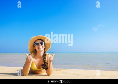 Glückliche Frau in Strohhut und Sonnenbrille am Sandstrand Stockfoto