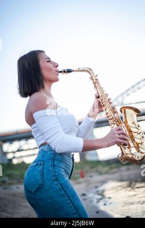 Frau spielt Saxophon bei Sonnenuntergang Stockfoto