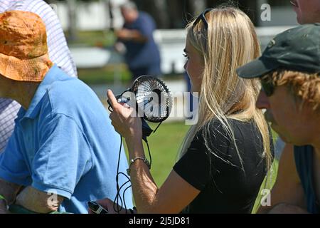 REEFTON, NEUSEELAND, JANUAR 5 2022; Eine junge Frau nutzt einen tragbaren Ventilator, um bei einem Country Track Meet, 5. Januar 2022, kühl zu bleiben. Stockfoto