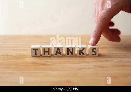 Dankeskonzept. Wort Dank auf Holzwürfel mit Finger zeigt Buchstaben s. Botschaft als Dankbarkeit, Ermutigung, Wertschätzung für Fürsorge, Hilfe, Hoffnung, Erfolg haben Stockfoto