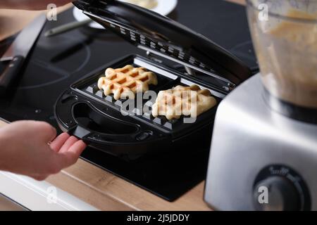 Waffeln in Waffeleisen in Nahaufnahme zu Hause kochen Stockfoto
