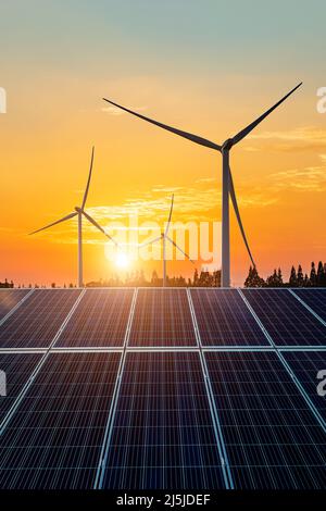 Windturbinen und Sonnenkollektoren bei Sonnenuntergang. Konzept der erneuerbaren Energien. Stockfoto