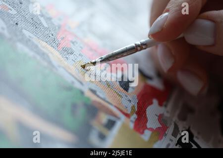 Frau malt Bild mit Aquarellen und hält Pinsel Stockfoto