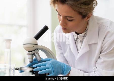 Eine Wissenschaftlerin verwendet während der Forschungsarbeiten das Mikroskop in einem Labor Stockfoto