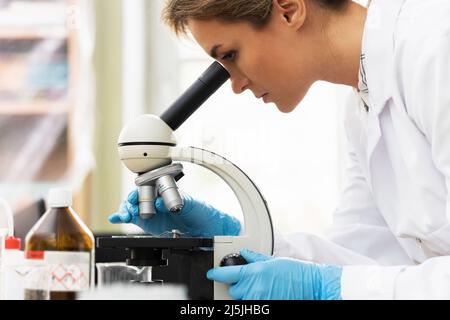 Eine Wissenschaftlerin verwendet während der Forschungsarbeiten das Mikroskop in einem Labor Stockfoto