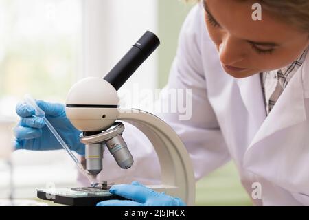 Eine Wissenschaftlerin verwendet während der Forschungsarbeiten das Mikroskop in einem Labor Stockfoto