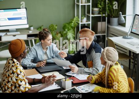 Vielfältiges kreatives Team, das in Geschäftstreffen zusammenarbeitet und die gemeinsame Arbeit an Projekten genießt, aus großer Perspektive Stockfoto