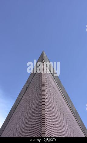 Detail der Ecke eines Ziegelgebäudes mit einem Betondach mit blauem Himmel im Hintergrund Stockfoto