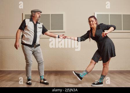 Ein Paar mit älteren Erwachsenen, das lindy Hop in einem Ballsaal tanzt Stockfoto