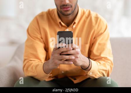 Junger Mann mit Smartphone zu Hause, Nahaufnahme Stockfoto