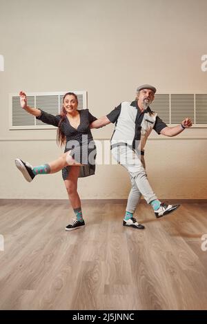 Ein Paar mit älteren Erwachsenen, das lindy Hop in einem Ballsaal tanzt Stockfoto