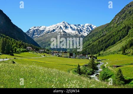 Plangeross, Österreich - 23. Juni 2016: Kleines Dorf in Pitztal mit verschneiten Tiroler Alpen im Hintergrund, bevorzugte Gegend für Skifahren und Wandern Stockfoto