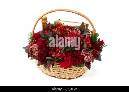 Großer Korb mit roten Blumen, Obst, Flasche Sekt und Süßigkeiten-Box auf weißem Hintergrund Stockfoto