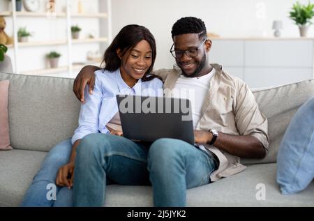 Porträt eines afroamerikanischen Paares, das zu Hause einen Laptop benutzt Stockfoto