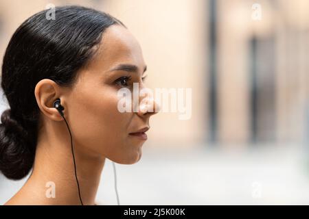 Ernst selbstbewusst junge arabische Frau Athlet Brünette in Kopfhörern auf Gebäude Hintergrund, Profil, Nahaufnahme Stockfoto