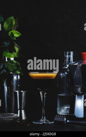 Klassischer alkoholischer Cocktail Espresso martini mit Wodka, Kaffeelikör, Sirup und Eis im Glas auf dunklem Thekenhintergrund, Bar-Werkzeuge, negativer Raum Stockfoto