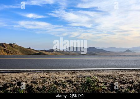 Leere Asphaltstraße und Berglandschaft unter blauem Himmel Stockfoto