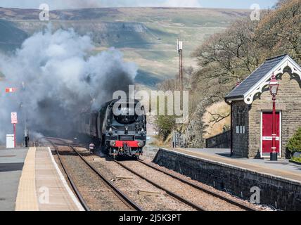 Das Bild zeigt die Southern Railways Battle of Britain Class 4-6-2 Dampflokomotive 34067 Tangmere, die sich dem Bahnhof Garsdale in den Cumbrian Dales nähert Stockfoto