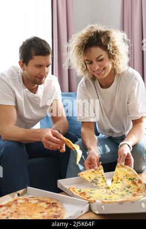 Glückliches Paar, das zu Hause leckere Pizza isst Stockfoto