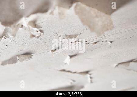 Die Farbe blättert aufgrund der Feuchtigkeit an der Decke des Badezimmers nach einem Wasseraustritt. Feuchtigkeit und Kondensation im Raum. Nahaufnahme Stockfoto