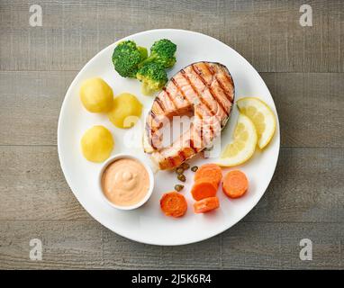 Platte mit gegrilltem Lachssteak und Gemüse auf Holztisch, Draufsicht Stockfoto